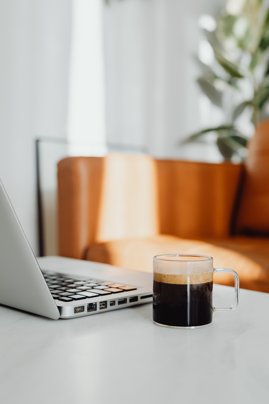 A Cup of Black Coffee Beside a Laptop